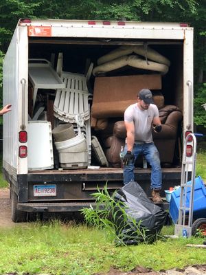 Two men performing local junk removal by loading furniture into a moving truck.