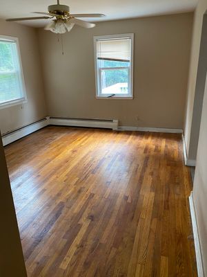 An empty room with hardwood floors and a ceiling fan.