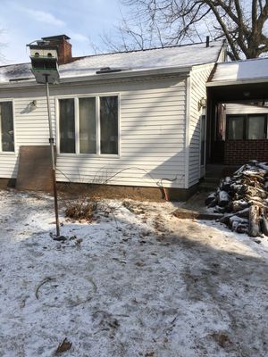 A house with snow on the ground and a snow shovel.